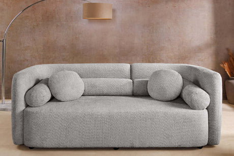 Szara sofa bouclé z zaokrąglonymi bokami i ozdobnymi poduszkami – nowoczesny mebel do eleganckiego salonu
