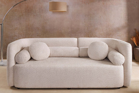 Beżowa sofa bouclé z zaokrąglonymi bokami i ozdobnymi poduszkami – nowoczesny mebel do eleganckiego salonu
