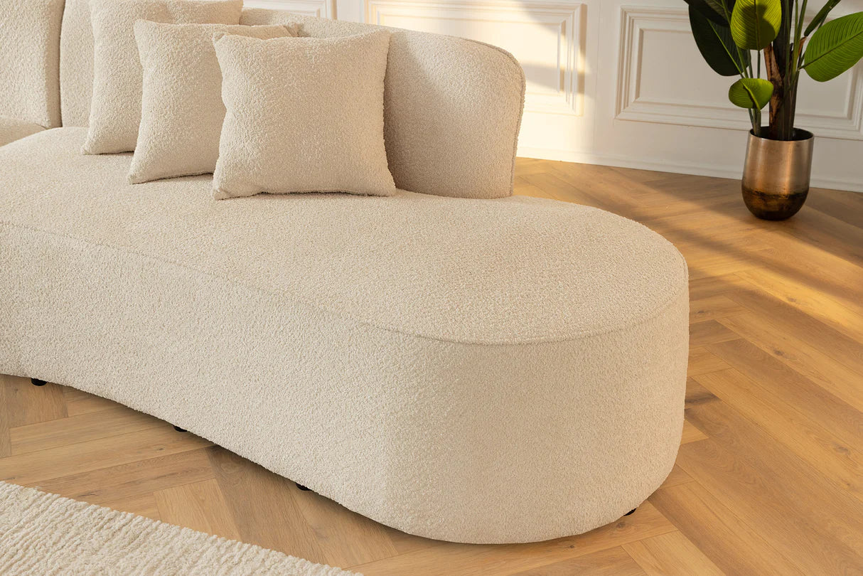Beżowa sofa z tkaniny bouclé o opływowym kształcie – nowoczesny mebel wypoczynkowy do eleganckiego salonu