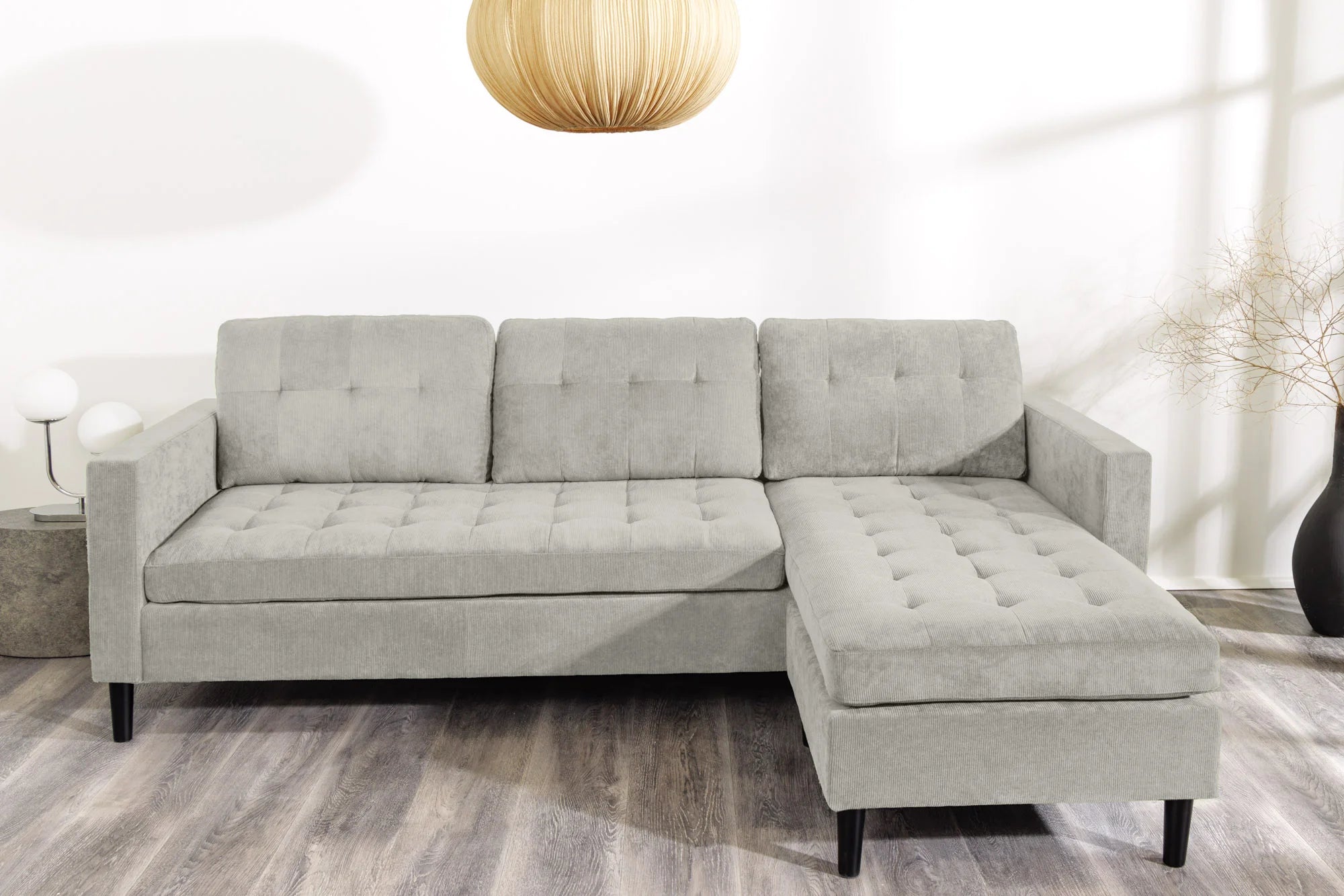 Nowoczesna sofa narożna w tkaninie cord, z otomaną lewą/prawą, tył tapicerowany, filcowe podkładki pod nogi