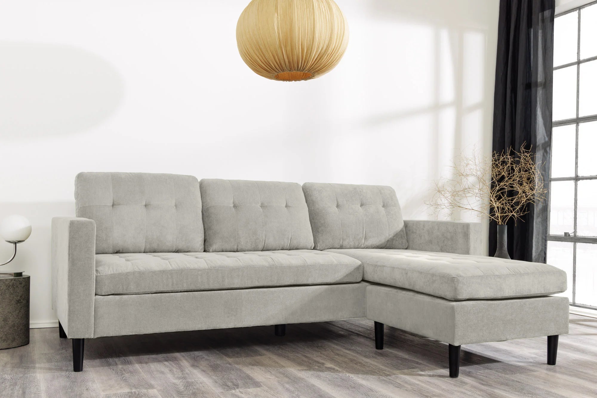 Nowoczesna sofa narożna w tkaninie cord, z otomaną lewą/prawą, tył tapicerowany, filcowe podkładki pod nogi