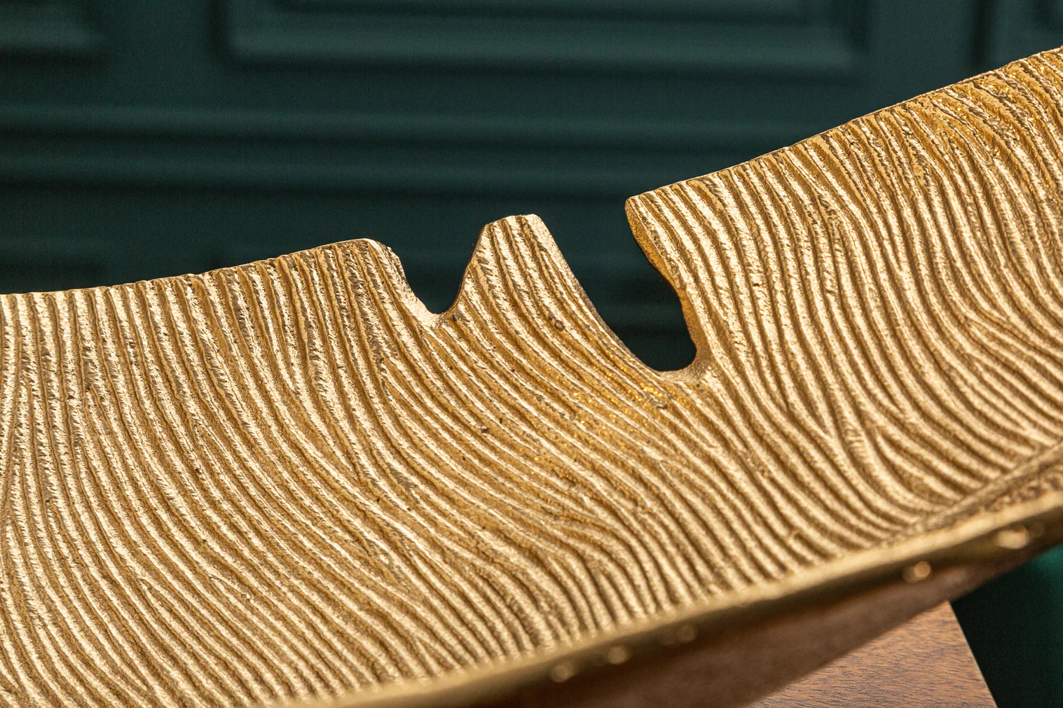 Złota metalowa misa w kształcie liścia na drewnianym stole, dekoracyjna ozdoba wnętrza