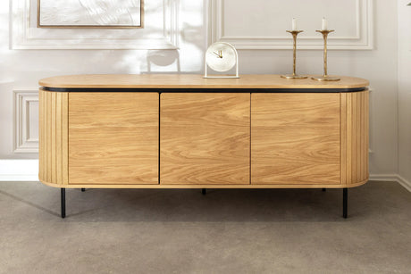 Nowoczesna owalna komoda z płyty MDF w naturalnym fornirze dębowym, z ryflowanymi frontami, czarnymi metalowymi nogami i drzwiami na magnes bez uchwytów – do salonu, jadalni lub biura.