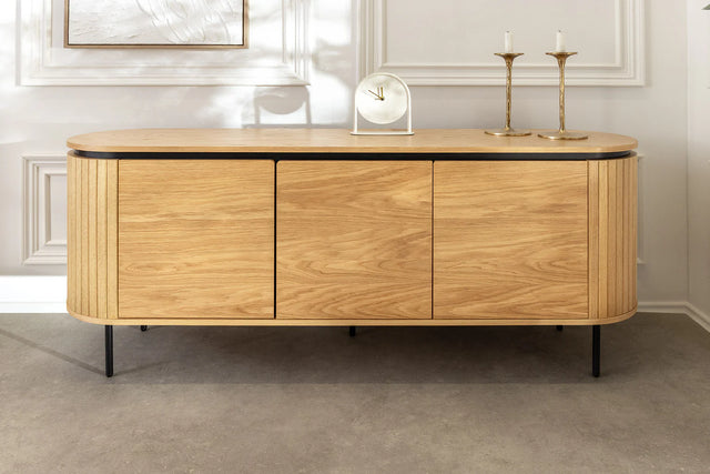 Nowoczesna owalna komoda z płyty MDF w naturalnym fornirze dębowym, z ryflowanymi frontami, czarnymi metalowymi nogami i drzwiami na magnes bez uchwytów – do salonu, jadalni lub biura.