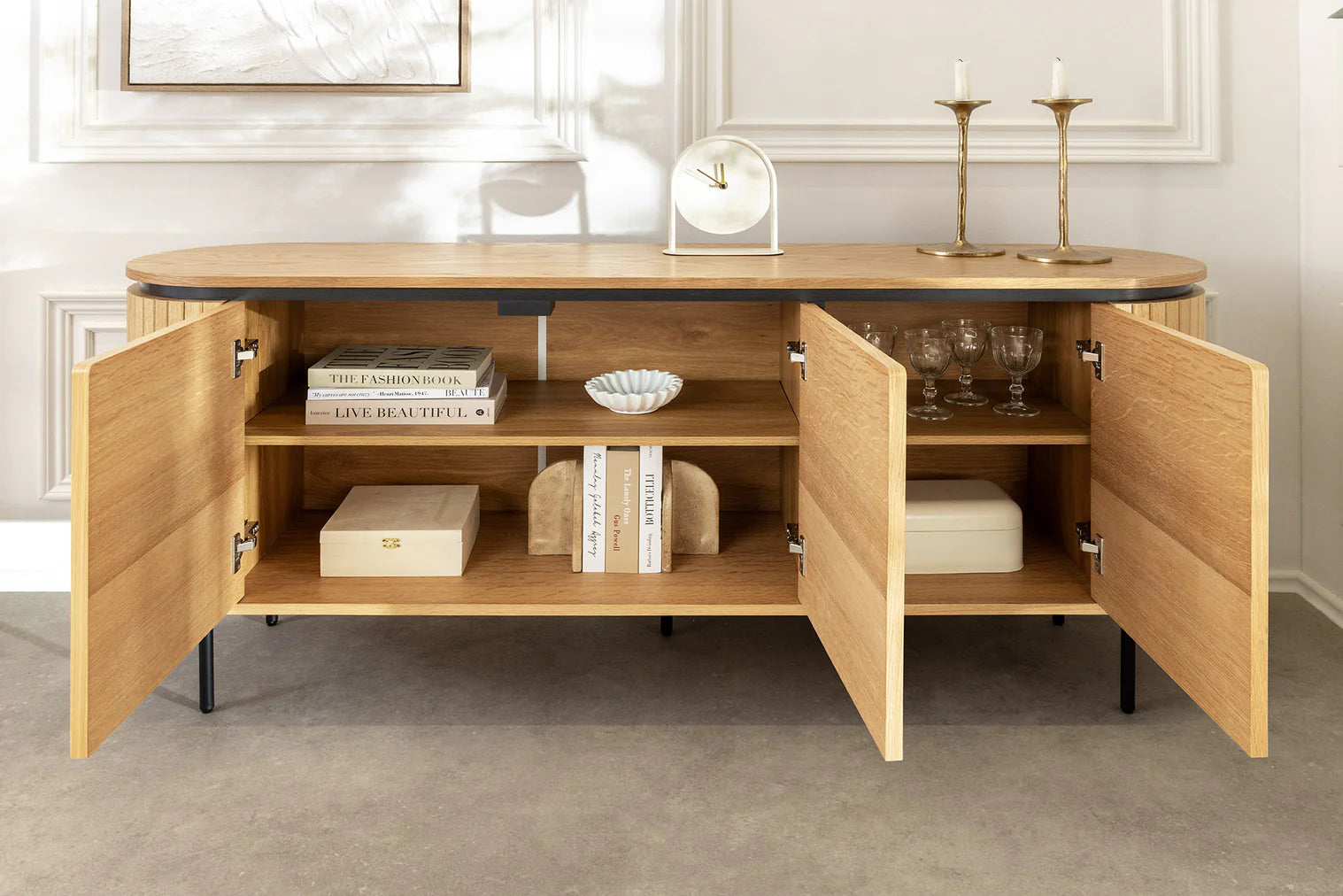 Nowoczesna owalna komoda z płyty MDF w naturalnym fornirze dębowym, z ryflowanymi frontami, czarnymi metalowymi nogami i drzwiami na magnes bez uchwytów – do salonu, jadalni lub biura.