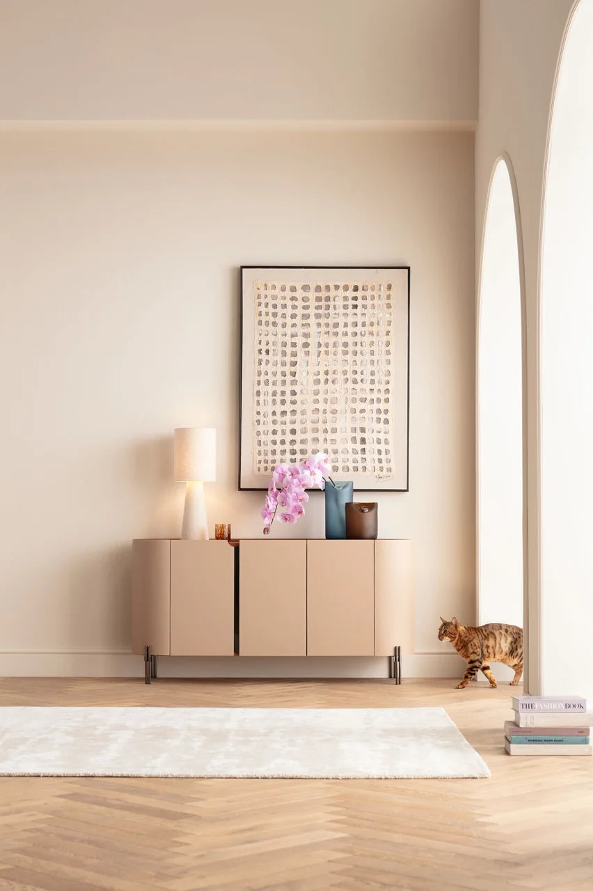 Beżowa komoda w ekoskórze na czarnych, stalowych nogach z zaoblonymi bokami i półkami w środku