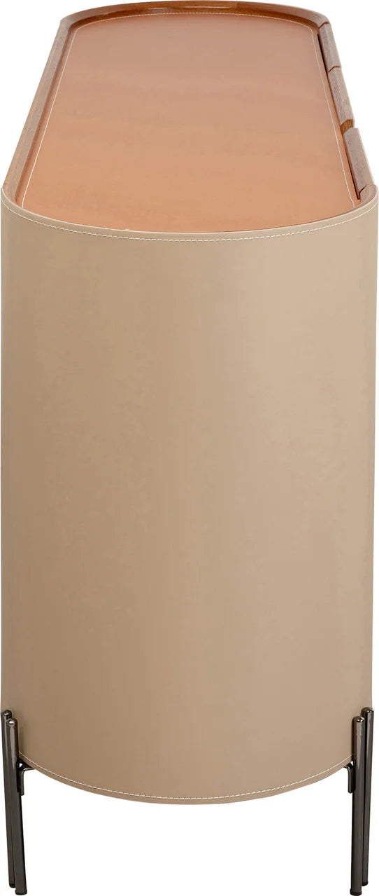 Beżowa komoda w ekoskórze na czarnych, stalowych nogach z zaoblonymi bokami i półkami w środku.