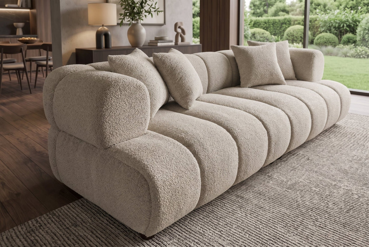 Nowoczesna beżowa sofa 255 cm, tkaninia boucle z zaokrąglonymi podłokietnikami i czterema poduszkami