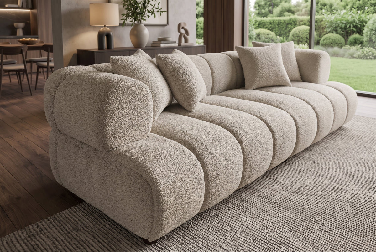 Nowoczesna beżowa sofa 255 cm, tkaninia boucle z zaokrąglonymi podłokietnikami i czterema poduszkami