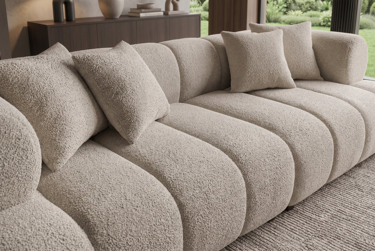 Nowoczesna beżowa sofa 255 cm, tkaninia boucle z zaokrąglonymi podłokietnikami i czterema poduszkami
