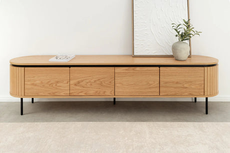 Nowoczesna szafka RTV z płyty MDF pokrytej fornirem dębowym, z zaokrąglonymi krawędziami, ryflowanymi bokami, czarnymi metalowymi nóżkami i drzwiami otwieranymi na magnes bez uchwytów.