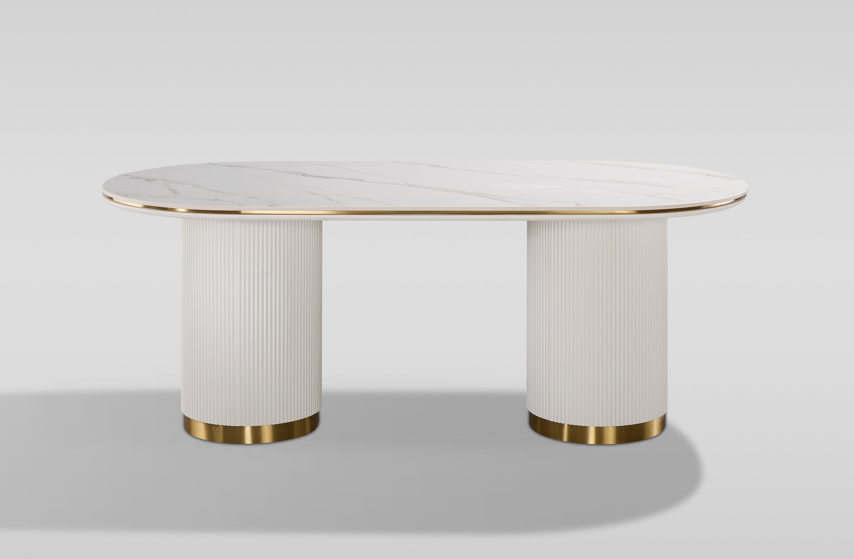 Nowoczesny stół w kolorze białym, owalnym blatem syntetycznym, na dwóch ryflowanych cylindrycznych nogach ze złotym wykończeniem.