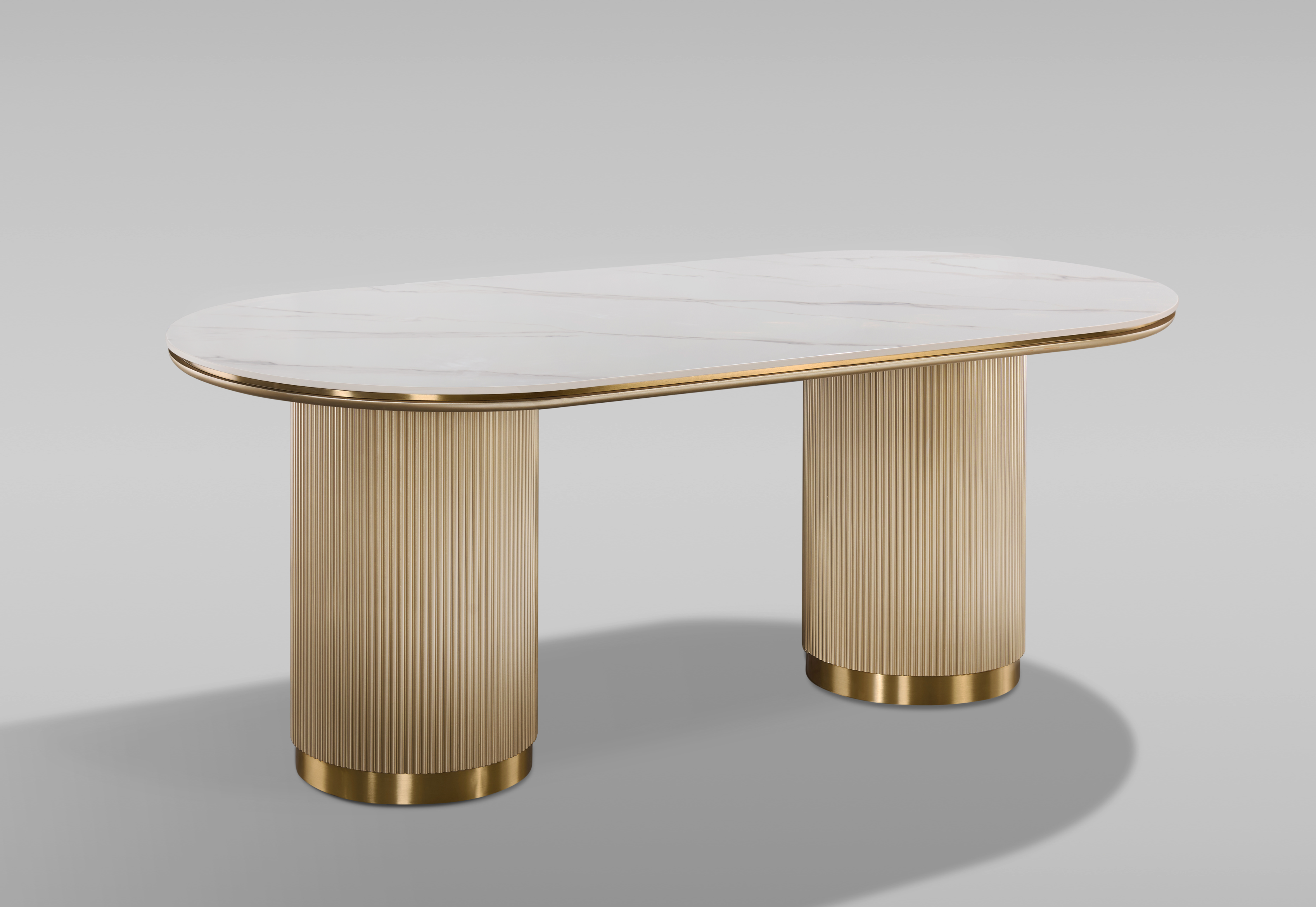 Nowoczesny stół w kolorze złota z białym owalnym blatem syntetycznym, na dwóch ryflowanych cylindrycznych nogach ze złotym wykończeniem.
