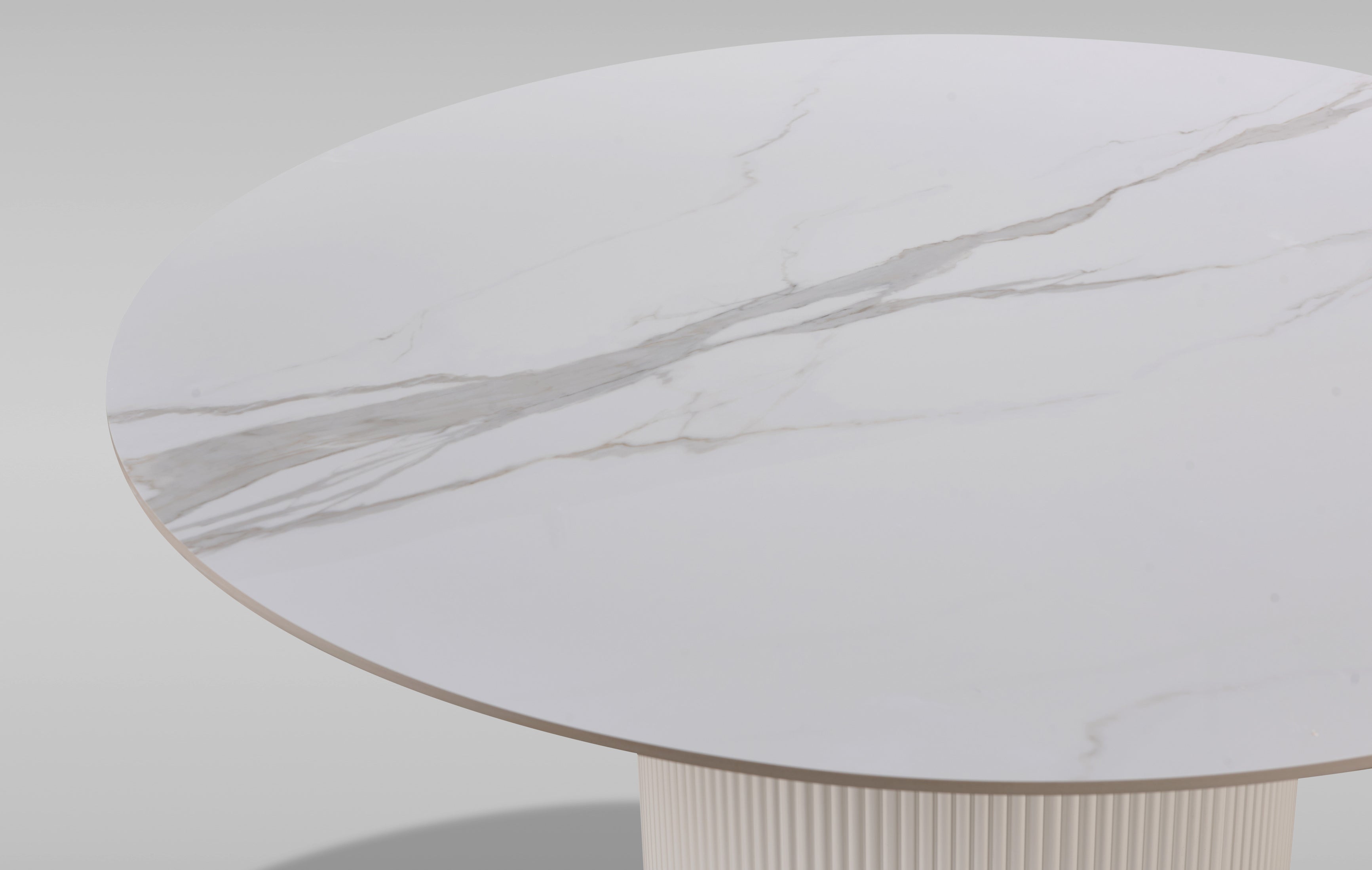 Nowoczesny stół w kolorze bielu / ecru z białym okrągłym blatem syntetycznym, na  ryflowanej podstawie ze złotym wykończeniem