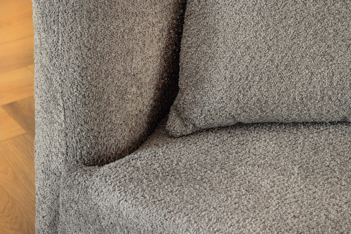 Szara sofa z tkaniny bouclé o opływowym kształcie – nowoczesny mebel wypoczynkowy do eleganckiego salonu