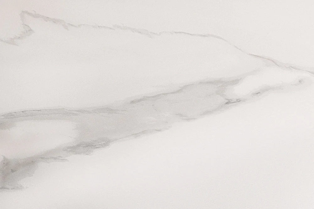 Okrągły stół z białym ceramicznym blatem imitującym marmur i czarną stożkową podstawą z metalu.